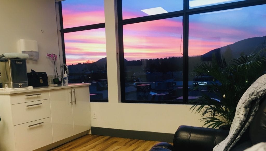 Mind Body Soul clinic window with sunset outside; highlighting the open house event in Kelowna