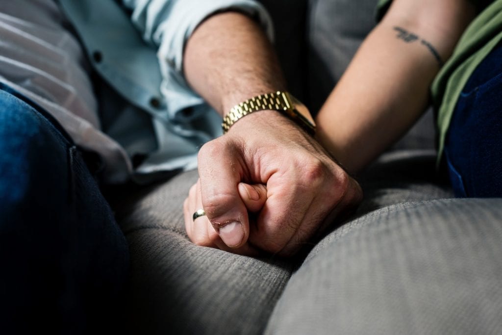 A couple holding hands as they lean on each other during a crisis