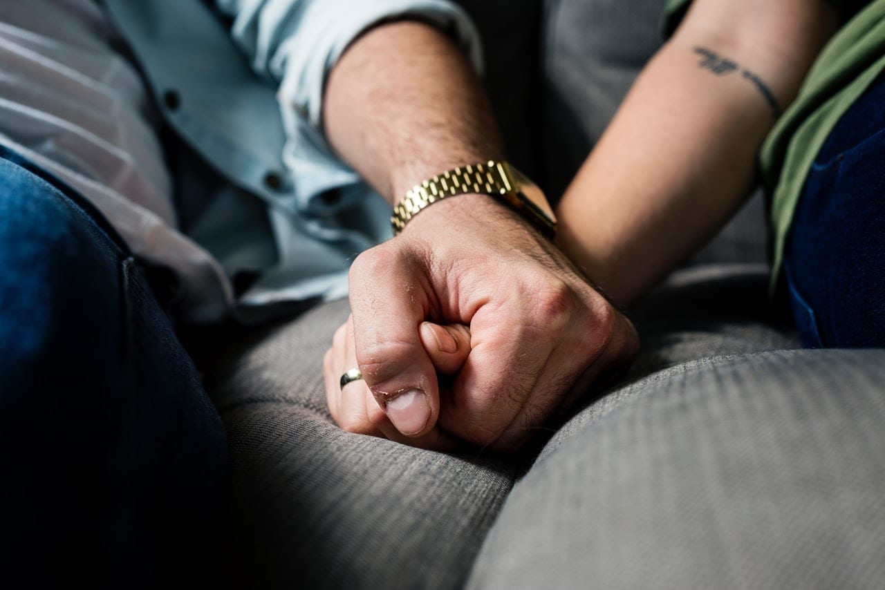 A couple holding hands as they lean on each other during a crisis