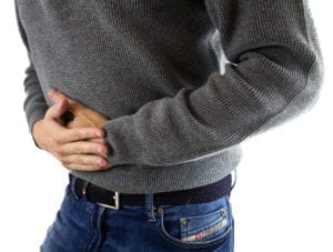 Closeup of mans torso holding stomach pain caused by Irritable Bowel Syndrome