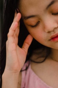 Woman holding head with headache, an area of treatment for neurokinetic therapy