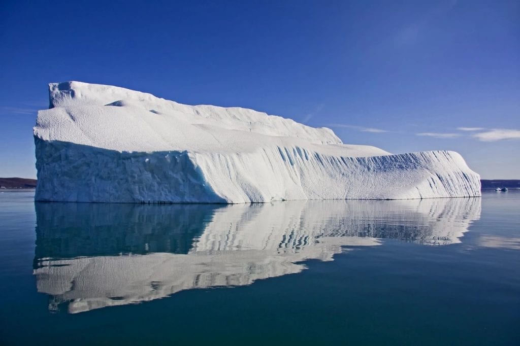 An Iceberg in calm water against blue skies, representing the depth of scars and the implications on the body for NKT