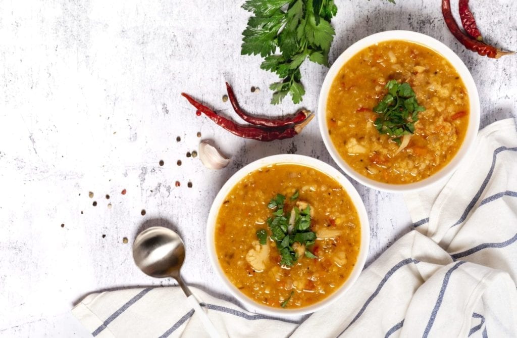 Lentil soup topped with cilantro on a marble countertop