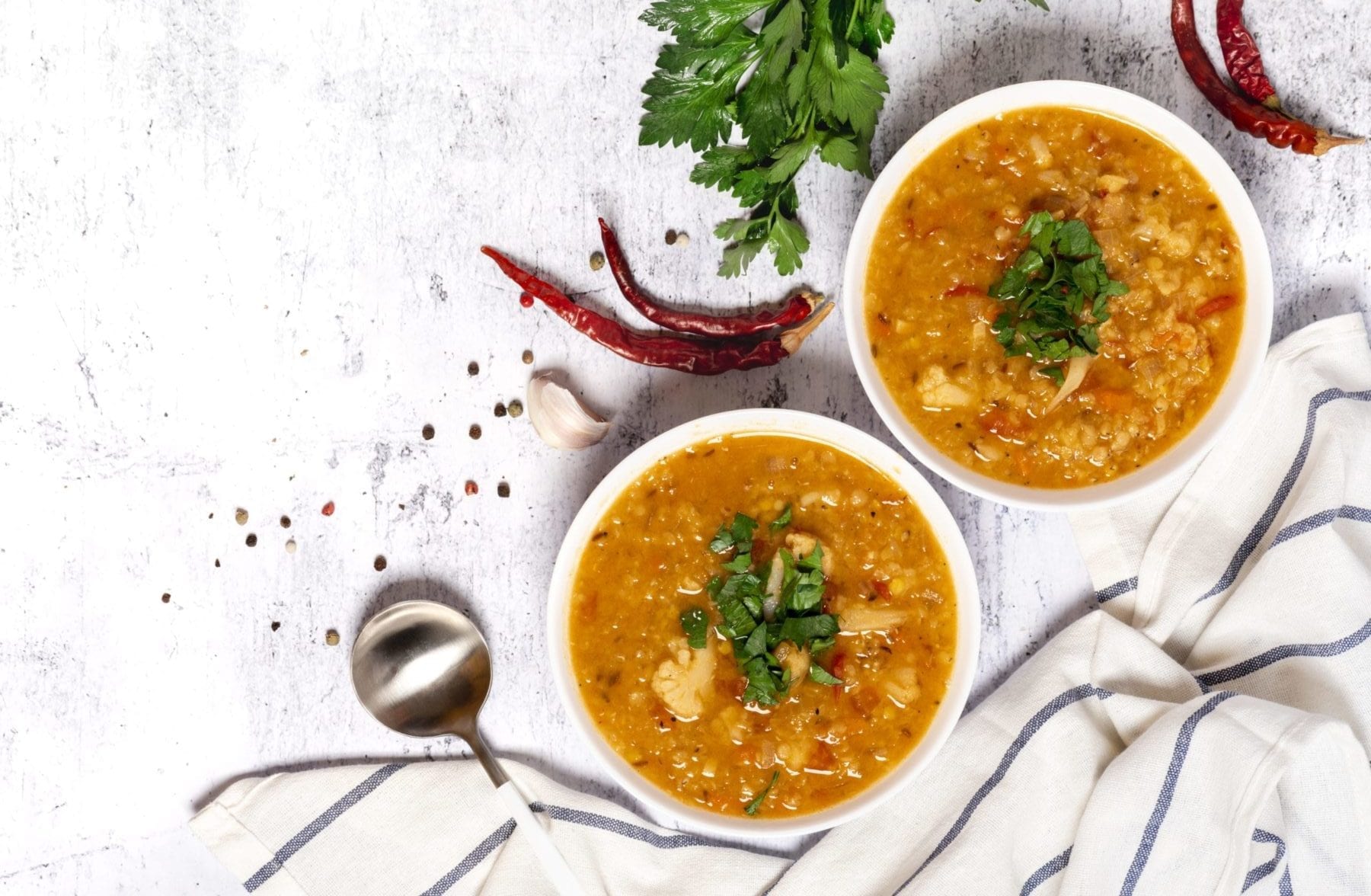 Lentil soup topped with cilantro on a marble countertop