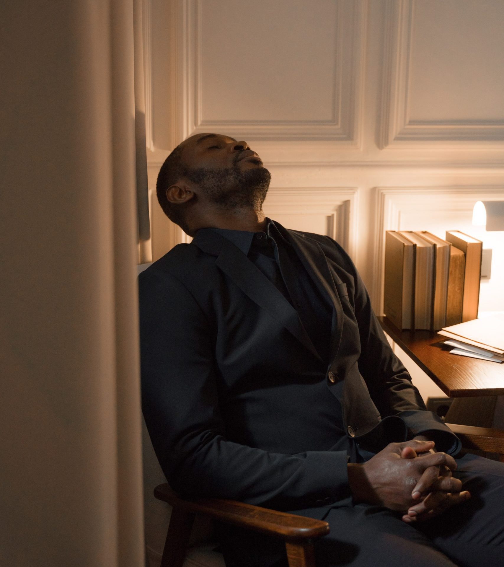 Seated tired man resting his head in a doorway due to symptoms of adrenal dysfunction