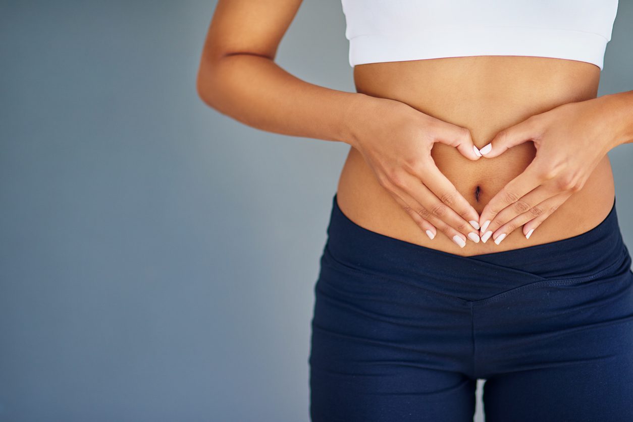 Cropped shot of a young woman making a heart shape on her stomach,highlighting IBS symptoms and causes
