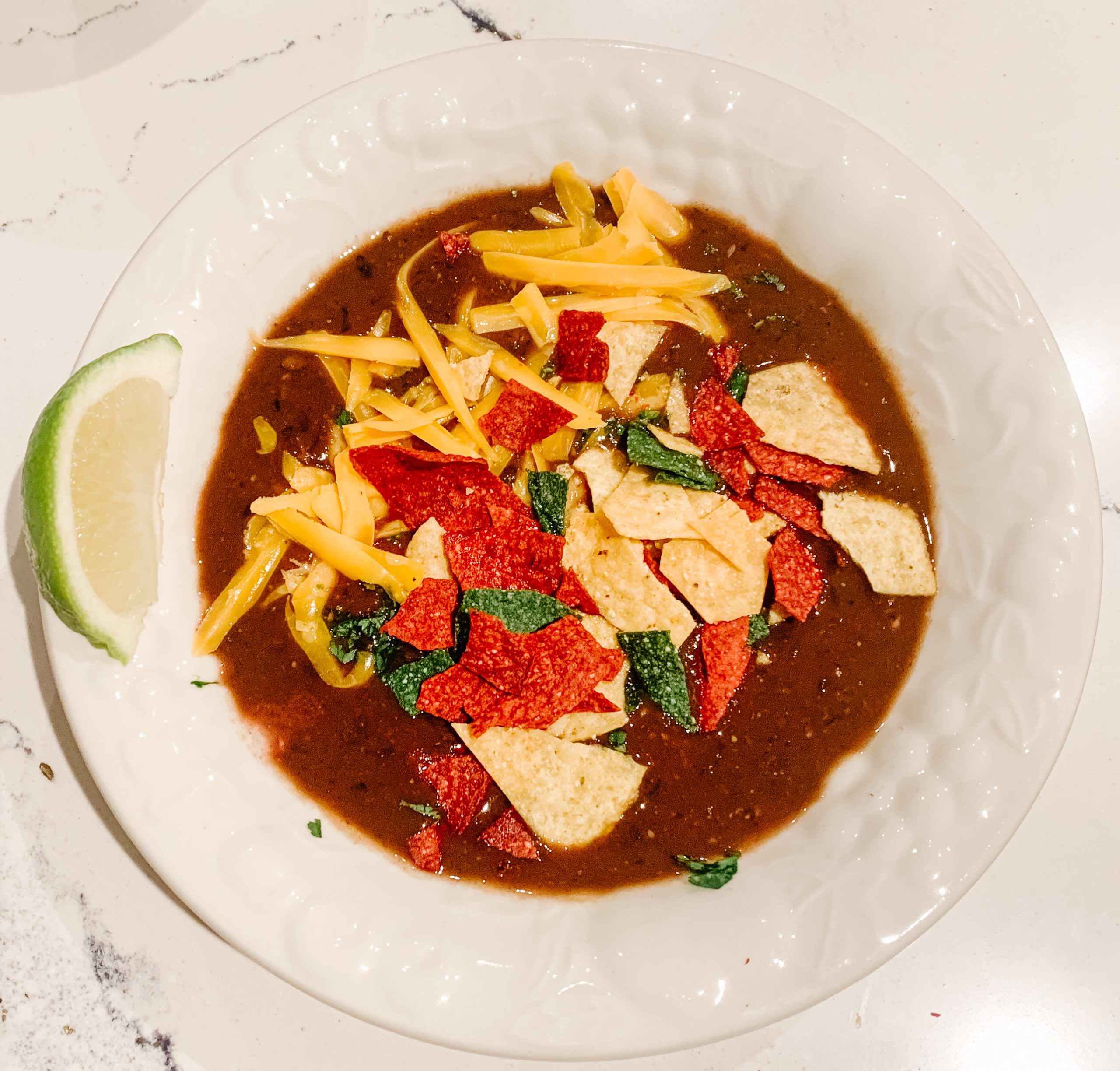 instapot black bean soup served in a white bowl with a lime on the side