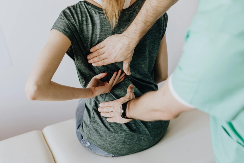 A woman having her back looked at by a professional asking about treatment options for back pain, including hypnotherapy.