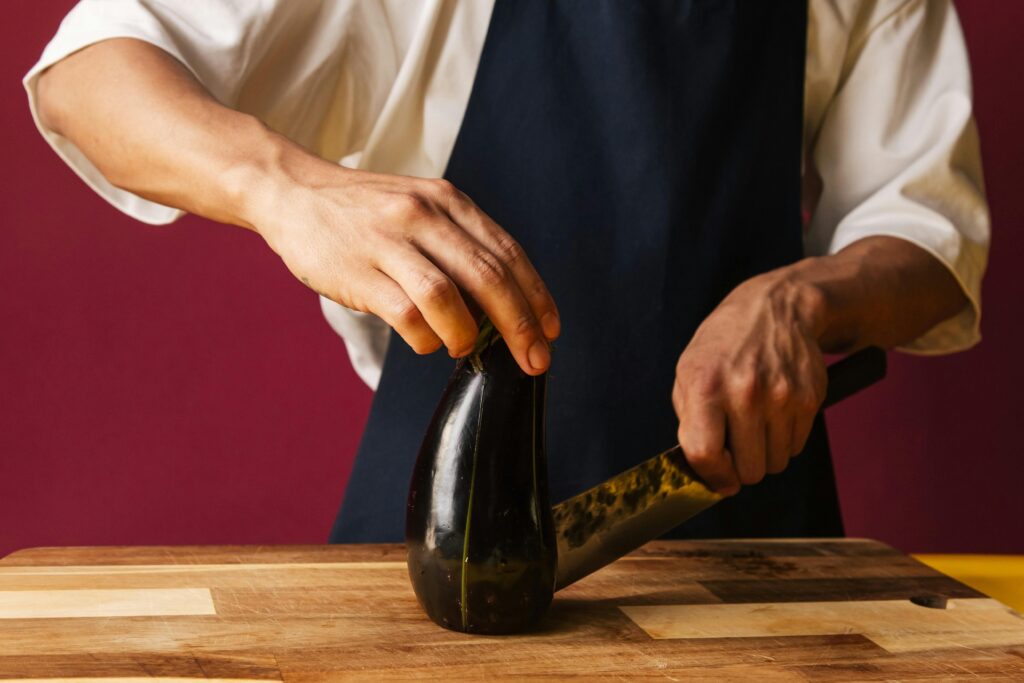 A man cutting up an aubergine in preparation for making eggplant dumplings alla parmigiana.